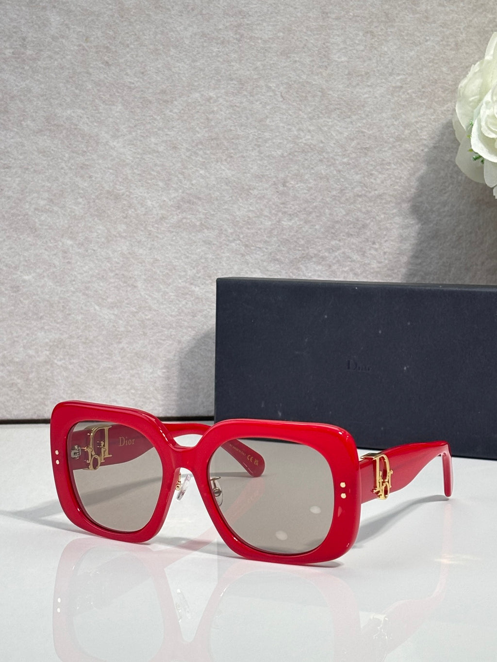 Red square sunglasses with clear-to-dark lenses and gold hinge detail