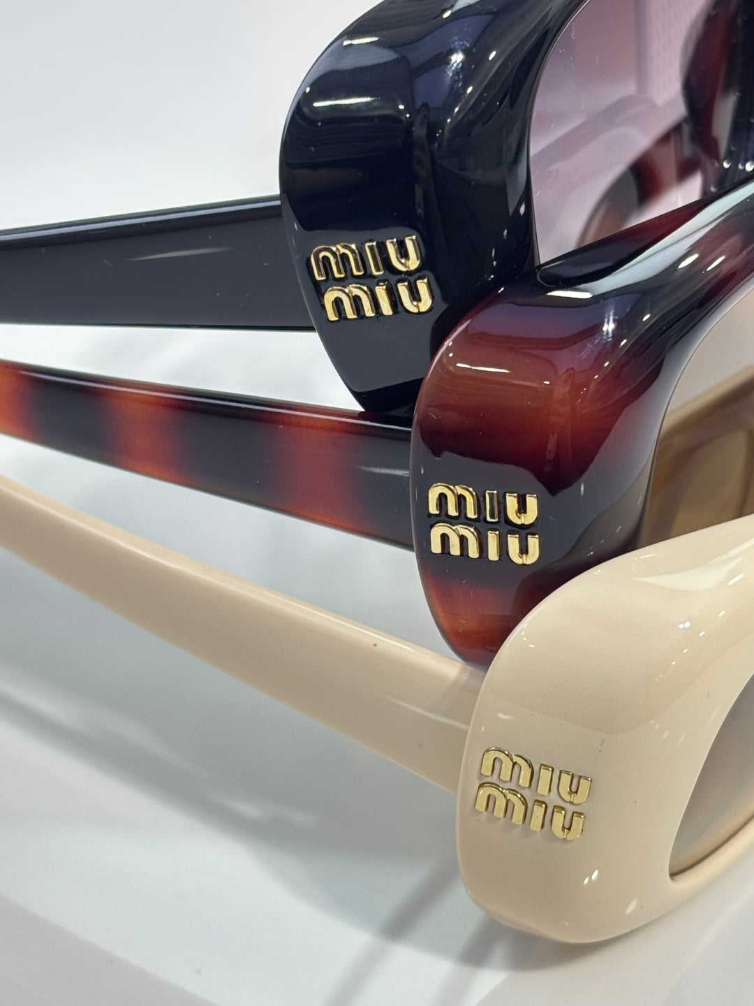 Close-up of glossy sunglasses frames in navy, burgundy, and cream tones