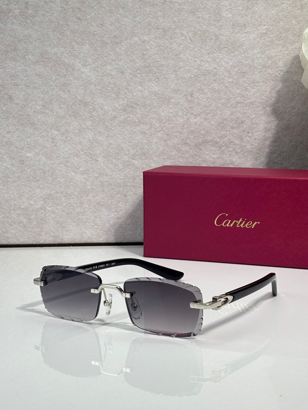 Cartier eyeglasses with dark lenses, silver metal frame, and gold detailing at the bridge.