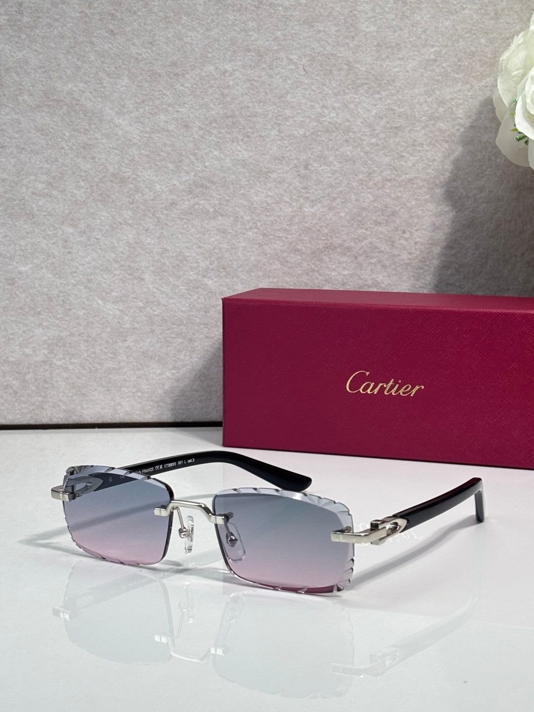 Cartier eyeglasses with light pink-tinted lenses, silver metal frame, and black temple tips.