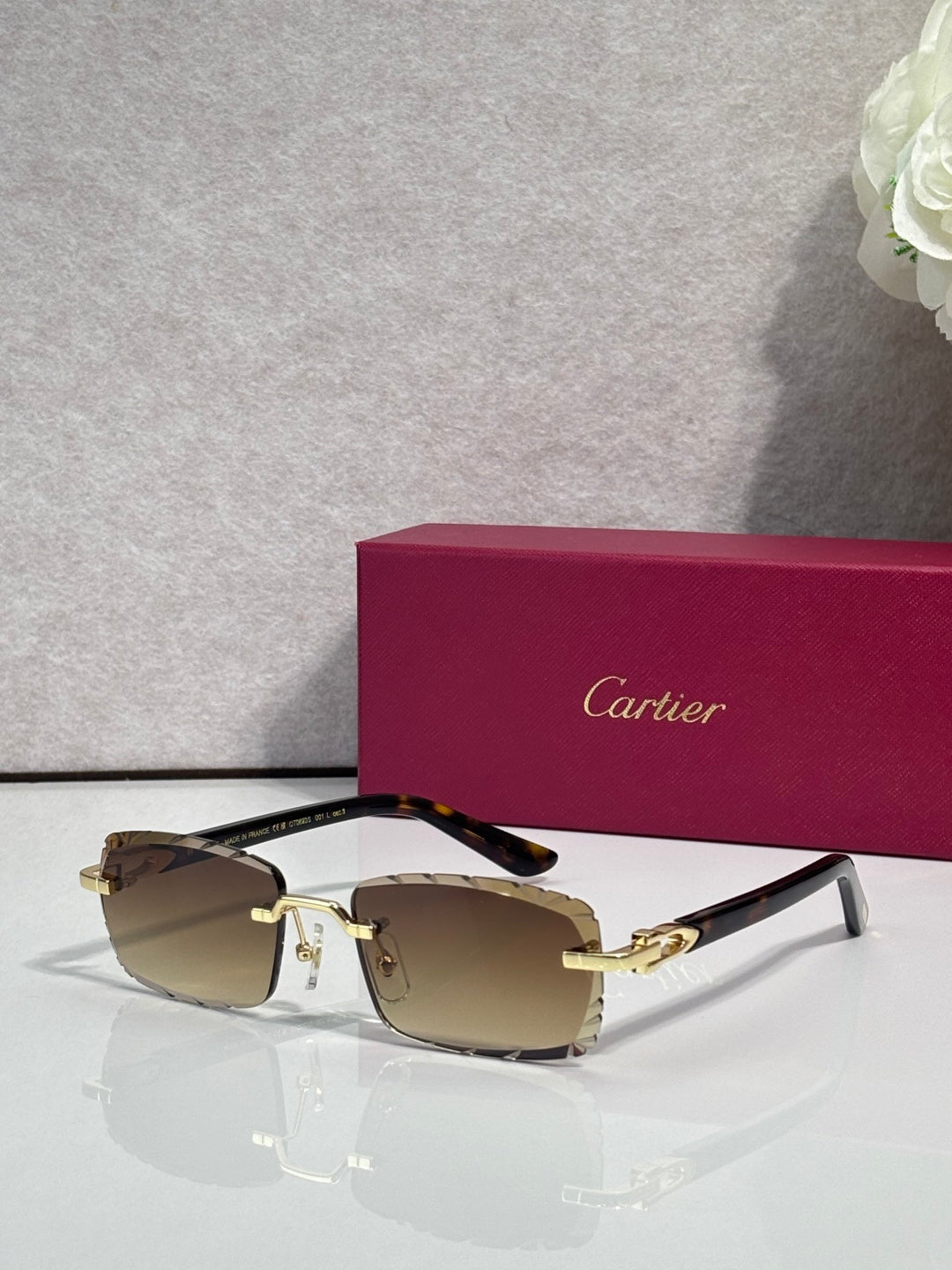 Cartier eyeglasses with brown-tinted lenses, gold metal frame, and black temple accents.