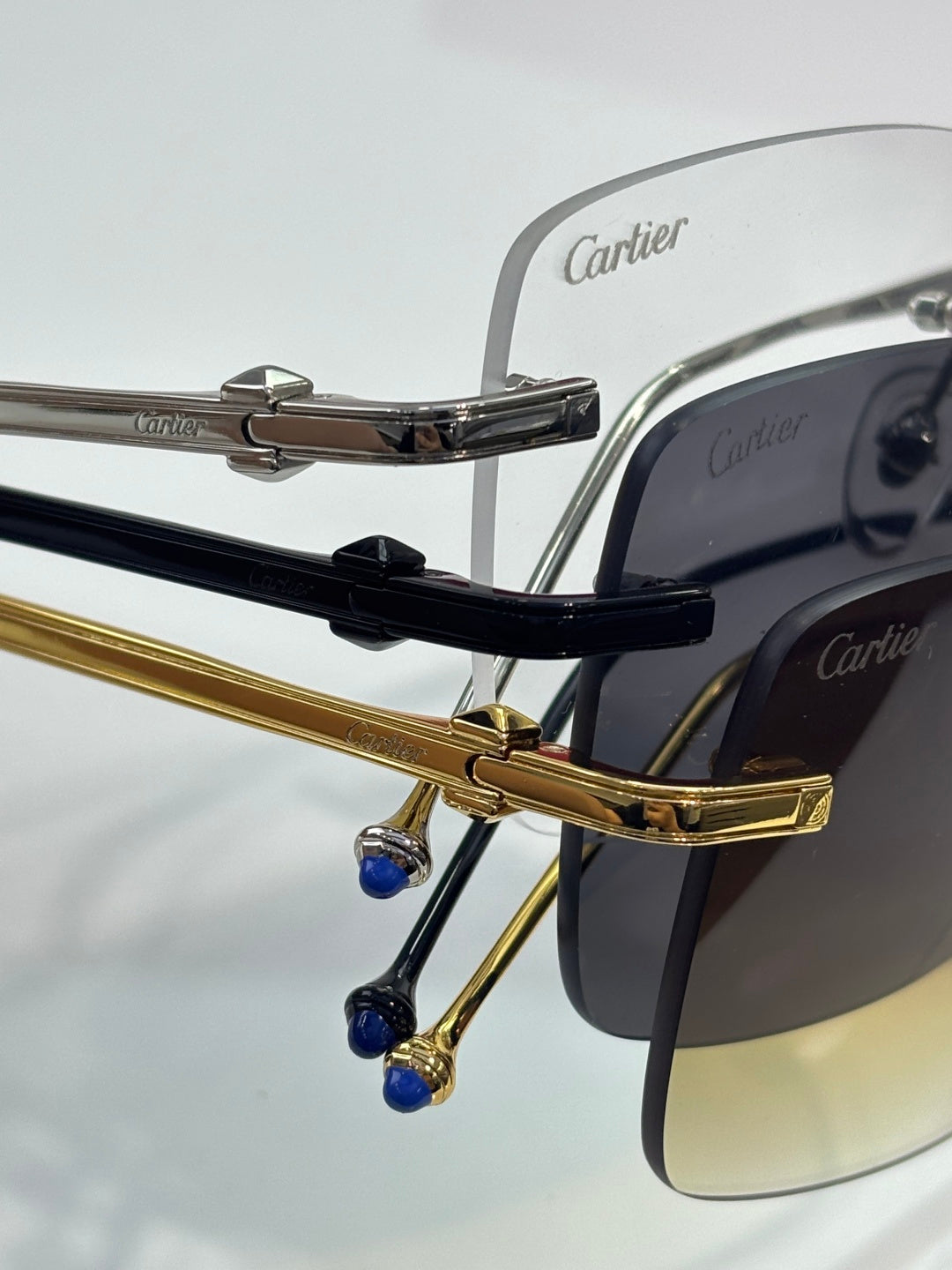 Close-up: metal eyeglasses hinges with blue accents, Cartier branding.