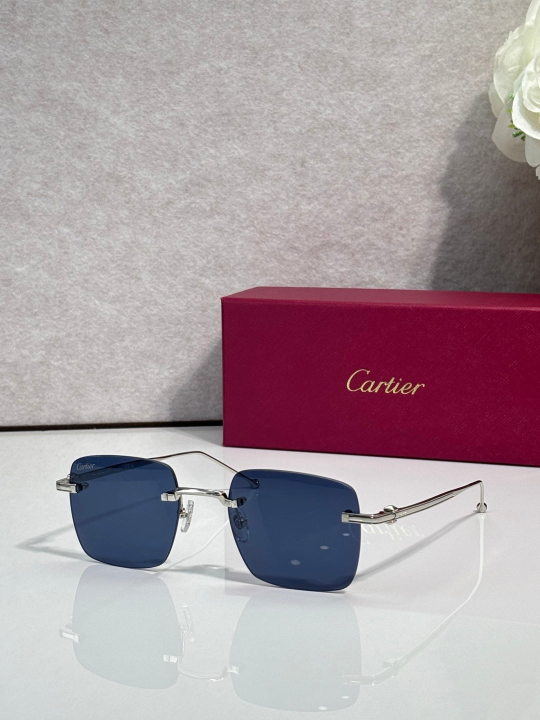 Blue-tinted sunglasses with dark metal frame, Cartier temple details.