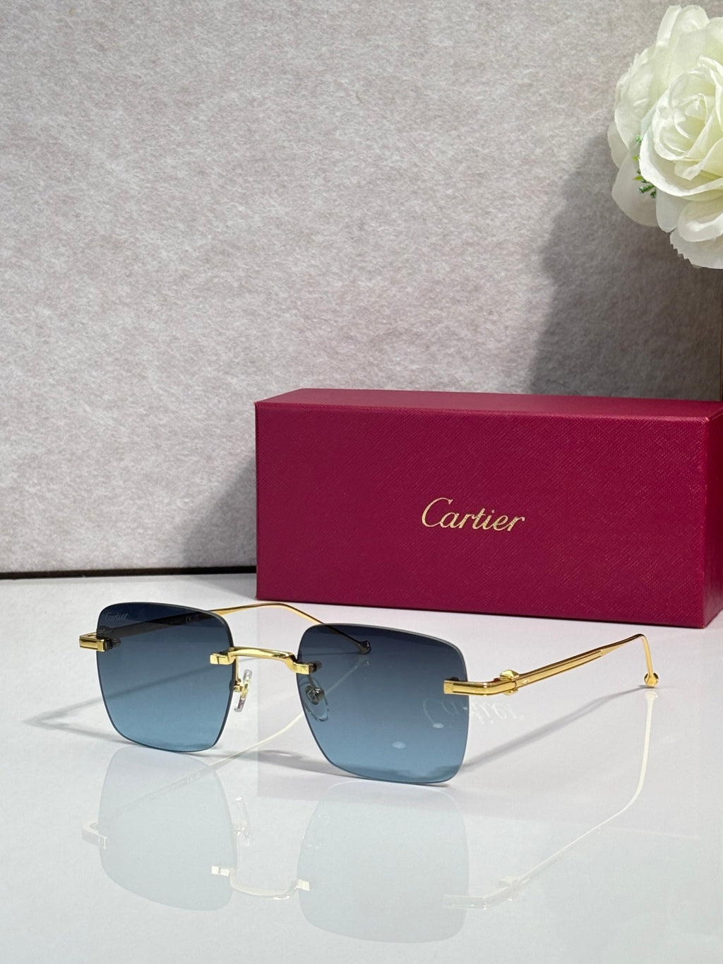 Cartier sunglasses with light blue gradient lenses and gold frame, clear side arms.