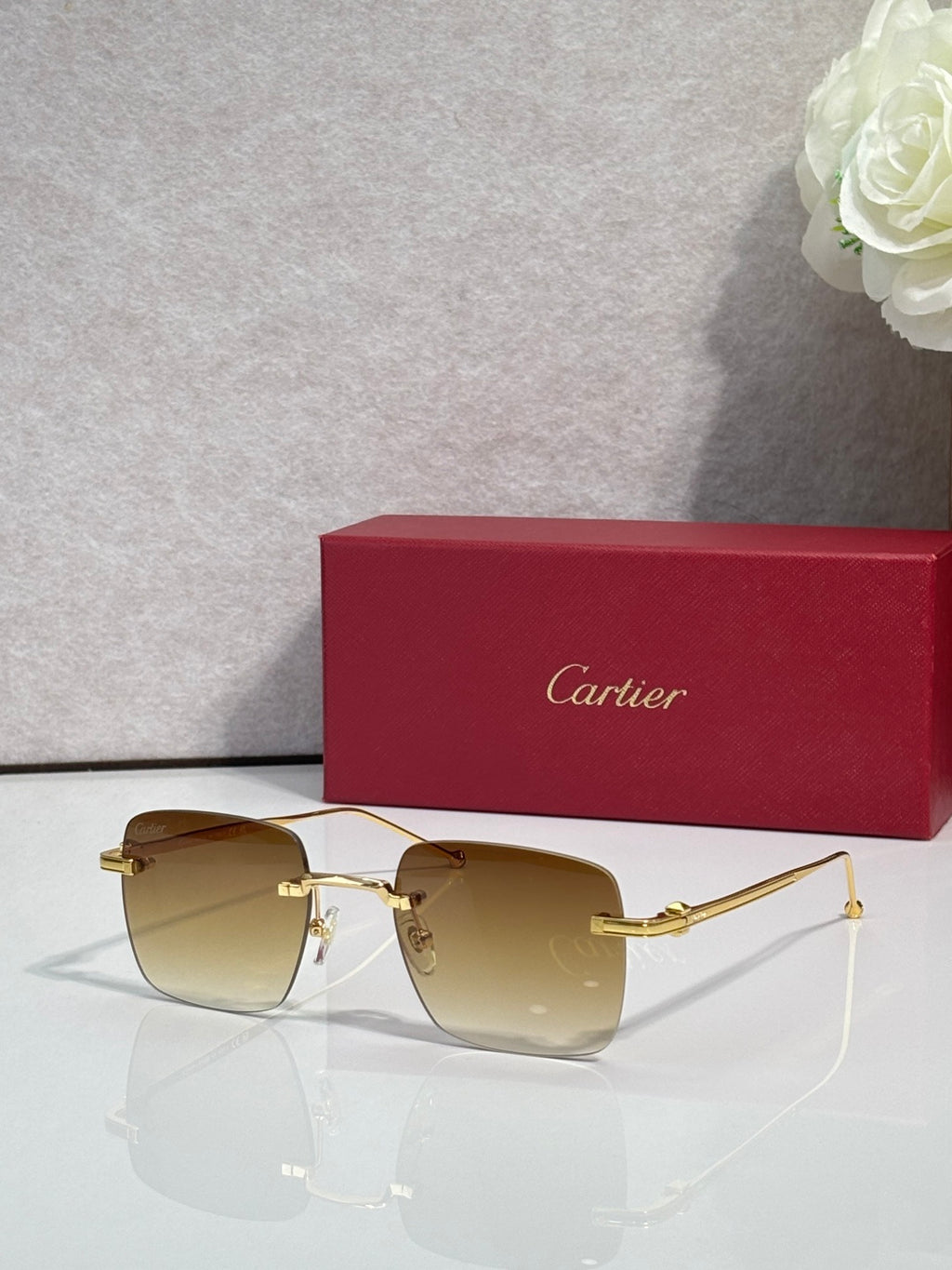 Cartier sunglasses with warm brown gradient lenses and gold frame, clear side arms.
