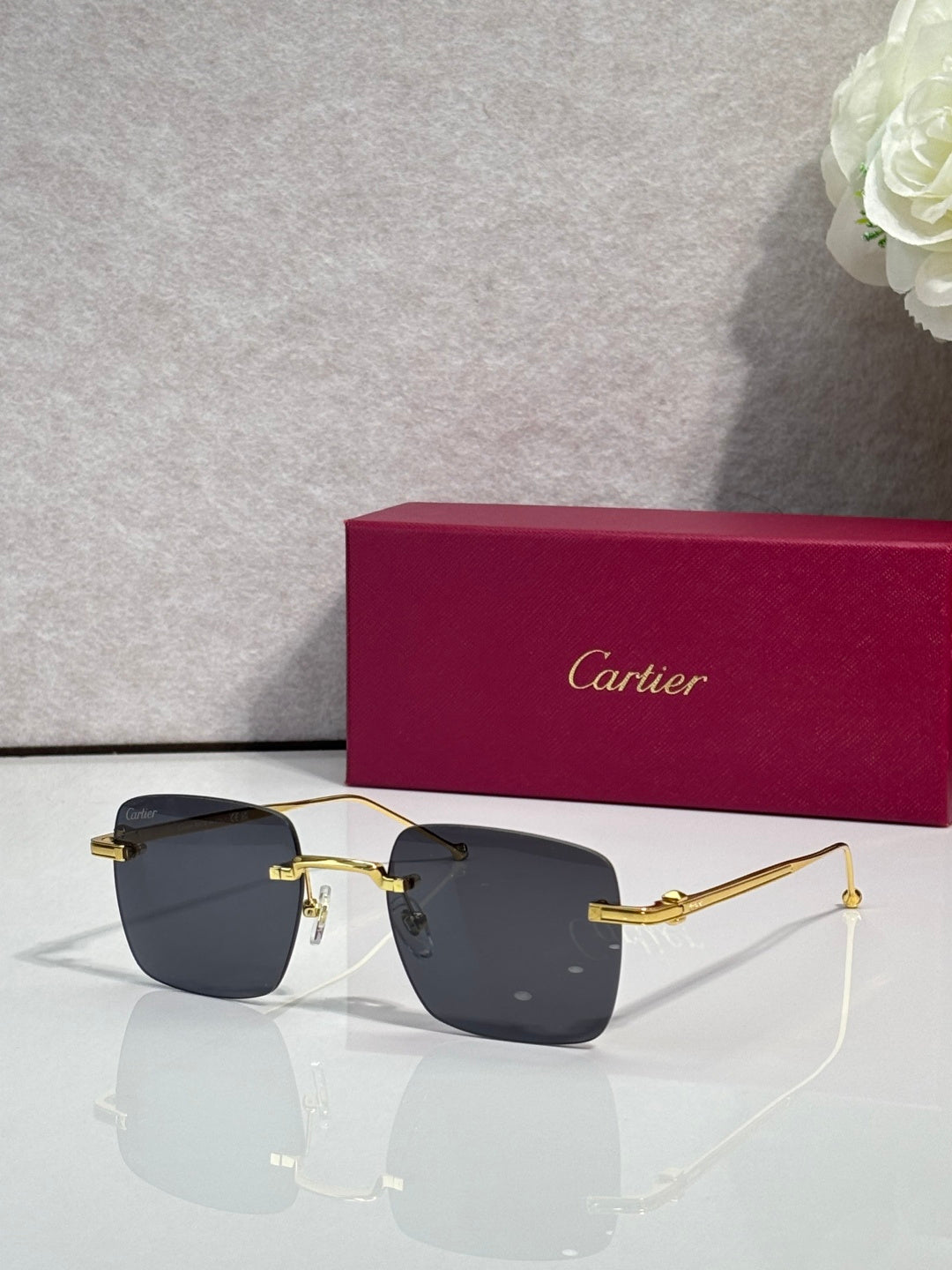 Cartier sunglasses with dark gray lenses and gold frame, clear side arms.