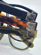 Close-up of stacked tortoiseshell and dark frames with gold-tone Dior hinges
