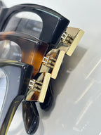 Close-up of dark eyeglass temple hinge with gold-tone detail and frame curvature