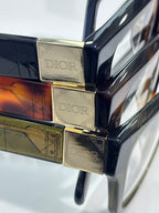 Close-up of stacked gold-tone Dior temple hinges with dark frame arms