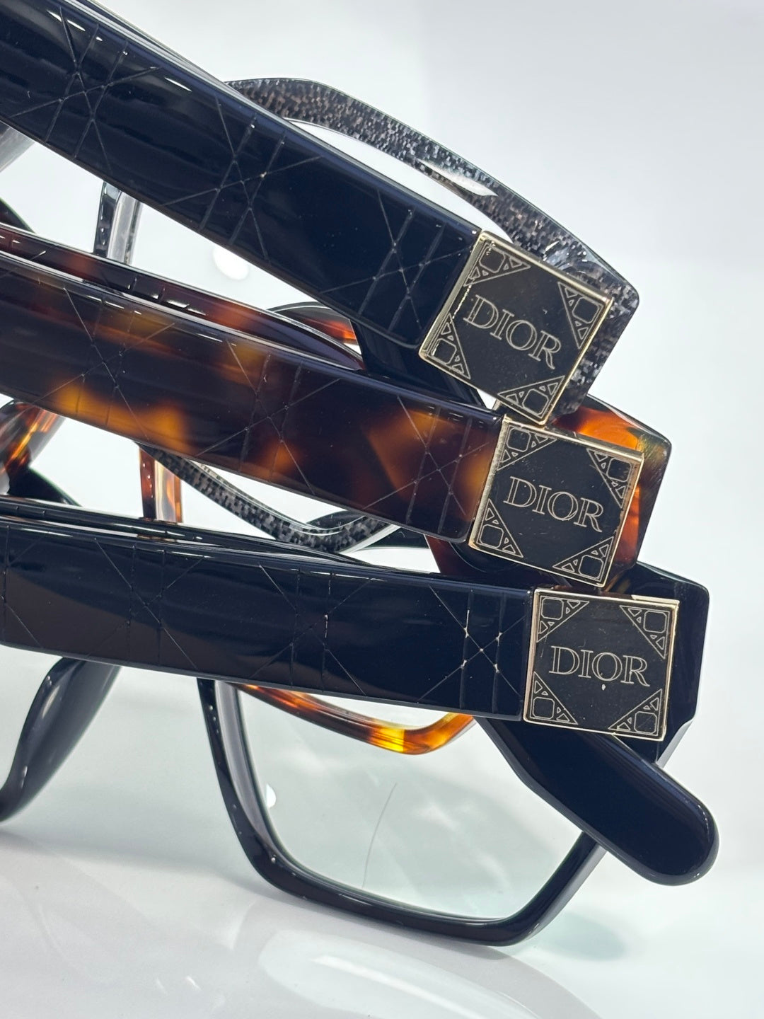 Dior eyeglasses, side close-up with gold Dior logo plaques and dark lenses