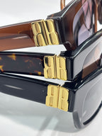 Balenciaga sunglasses close-up of gold logo hinge on brown and black frames