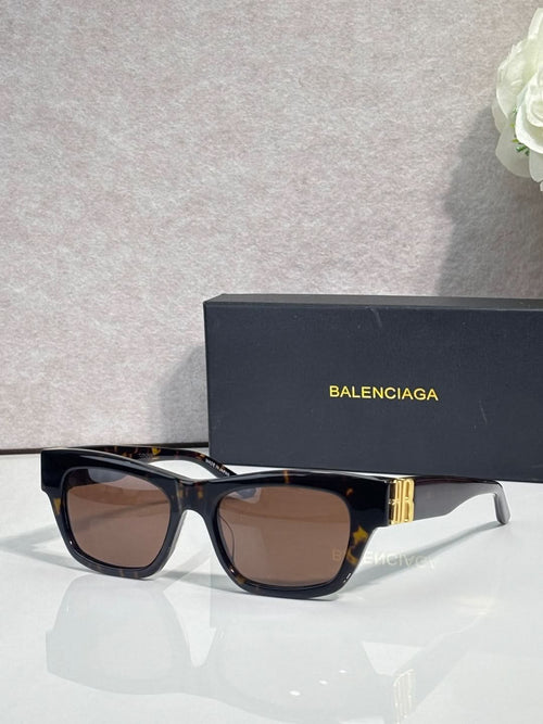 Balenciaga sunglasses with black frame, gold details, and dark brown tinted lenses