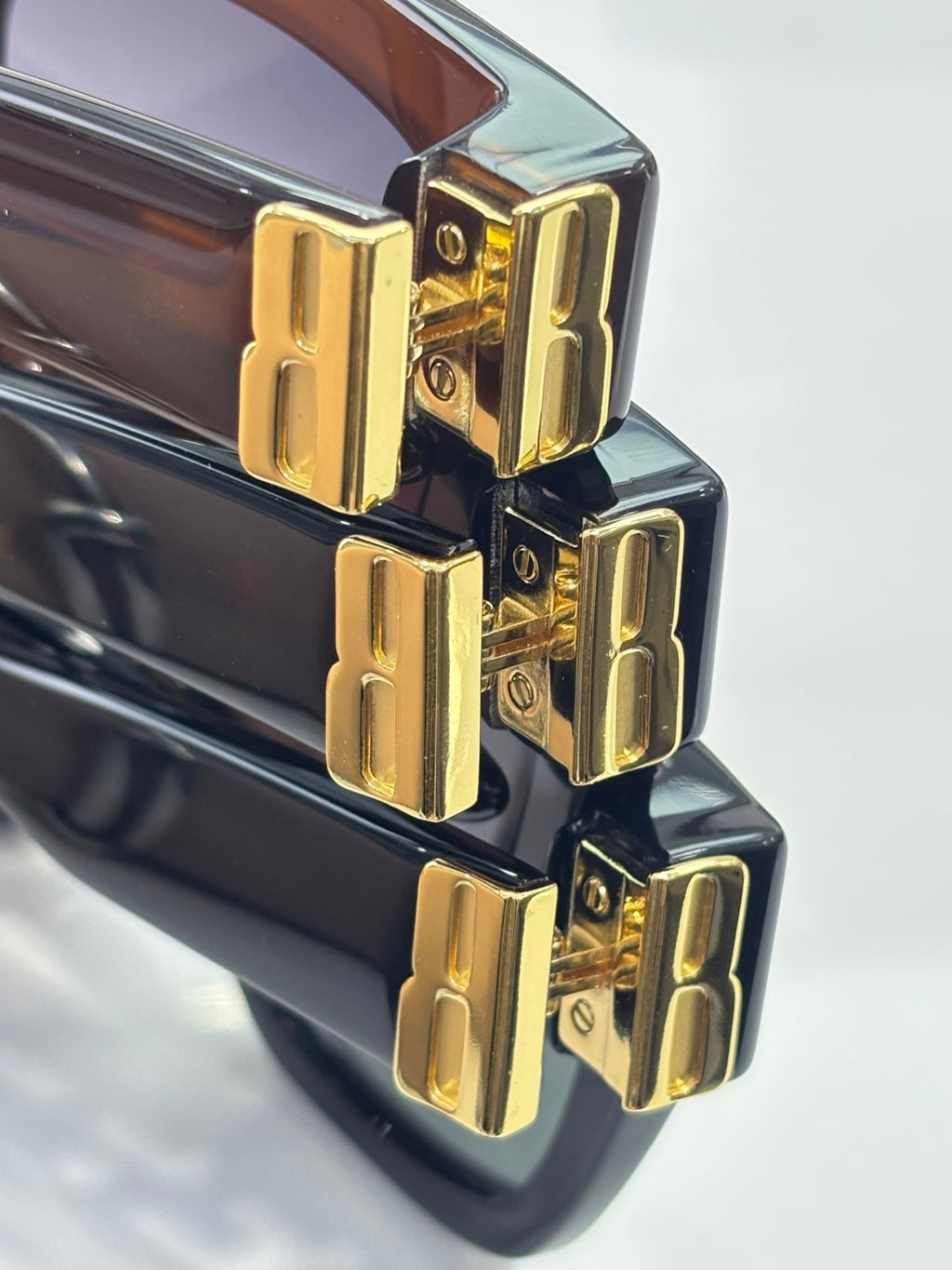 Balenciaga sunglasses close-up of gold logo hinge on glossy black frames