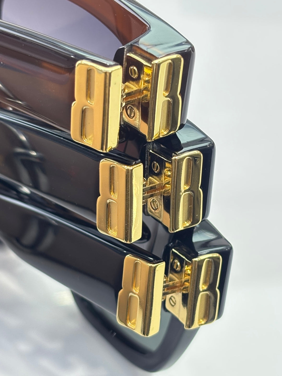 Balenciaga sunglasses close-up of gold logo hinge on glossy black frames