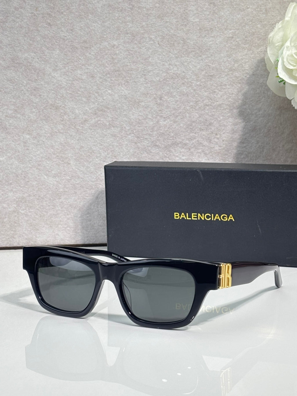 Balenciaga sunglasses with black frame, gold details, and gray-green tinted lenses