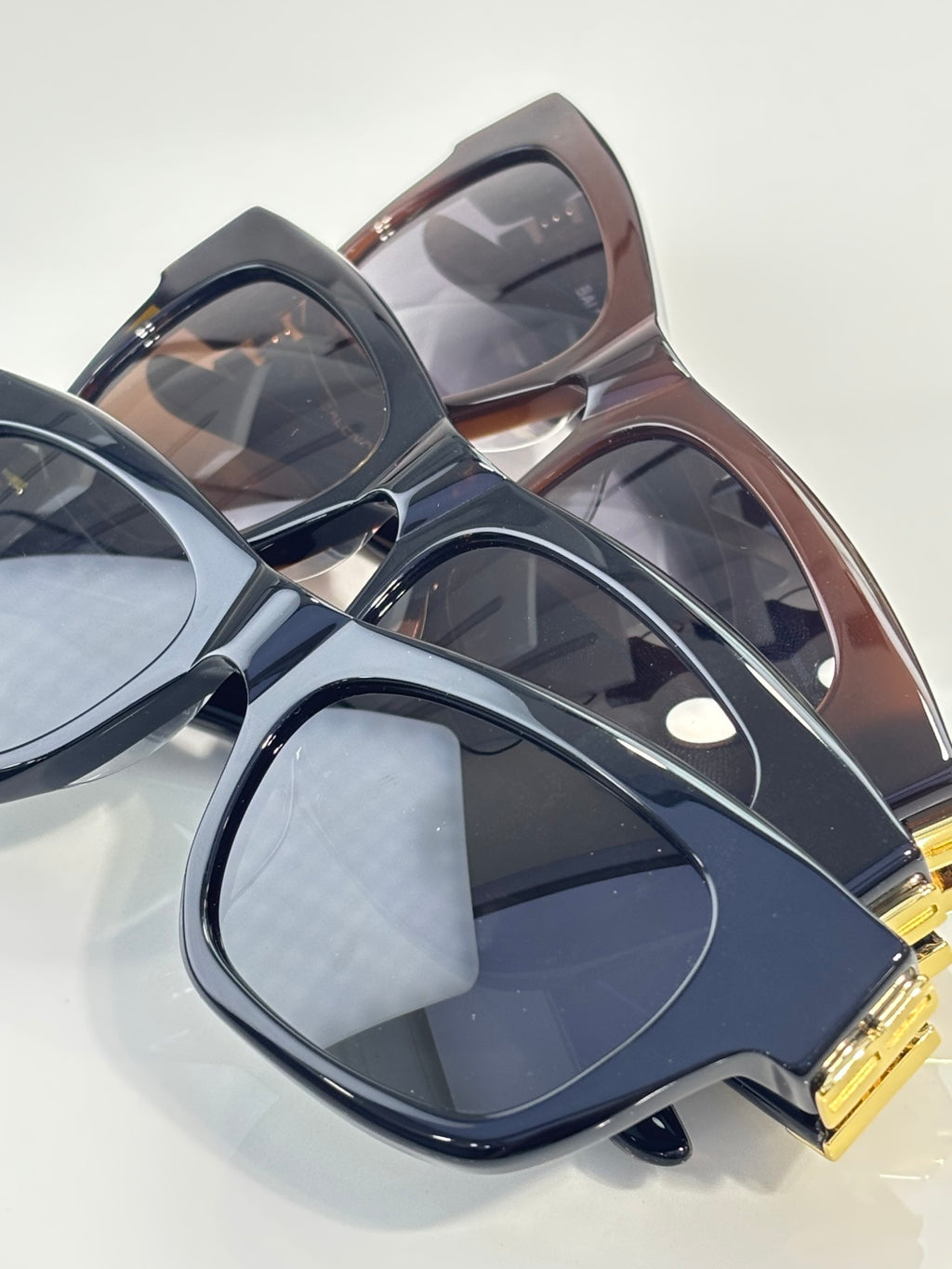 Balenciaga sunglasses overlapping with dark blue, brown, and black frames, gold details