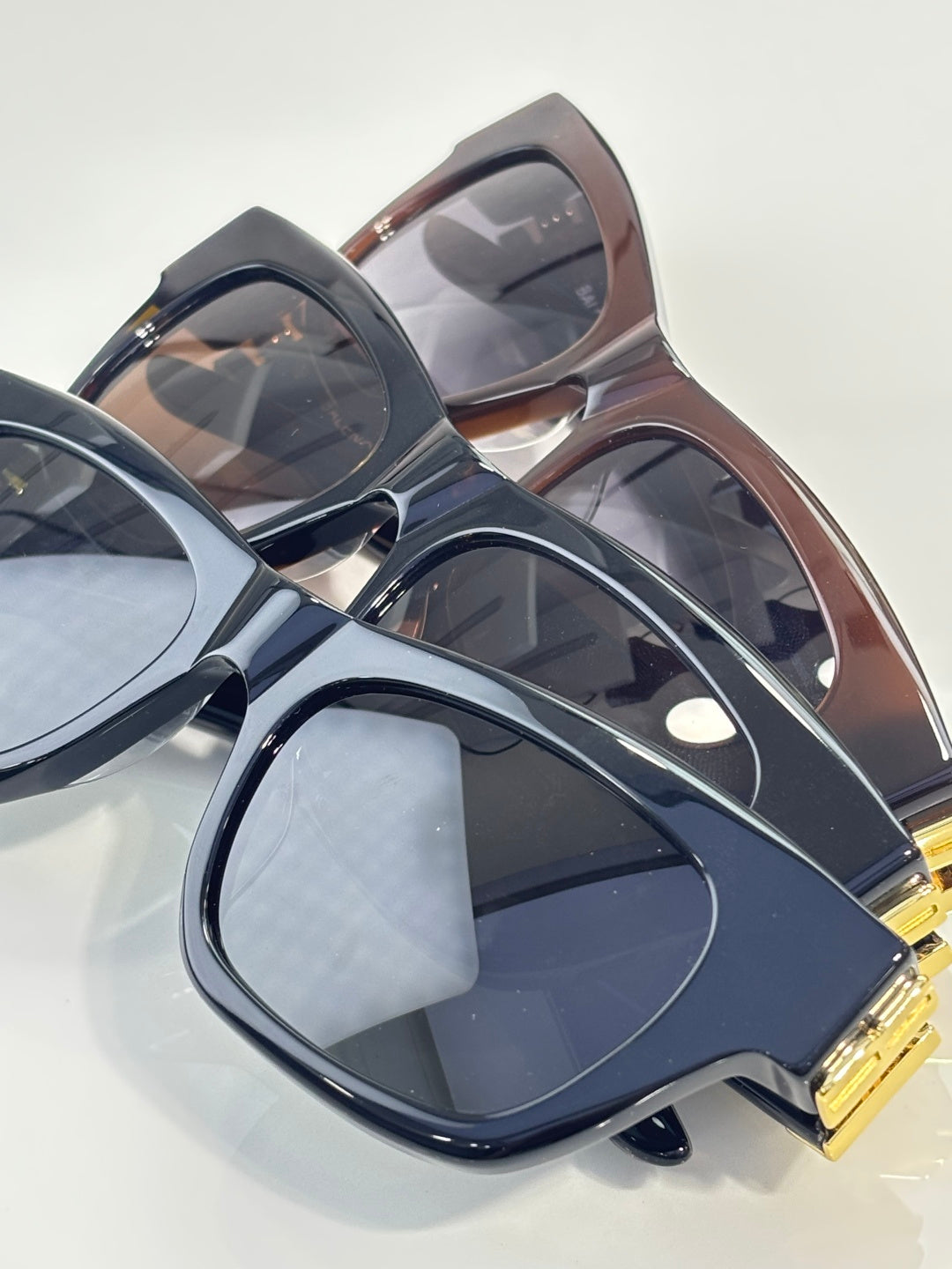 Balenciaga sunglasses overlapping with dark blue, brown, and black frames, gold details