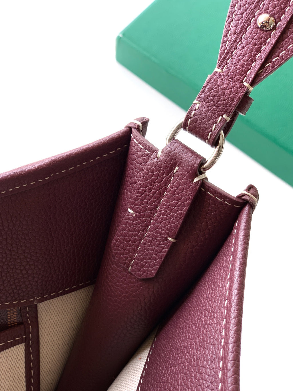Maroon Goyard bag with top hardware rings and adjustable strap, pebbled leather