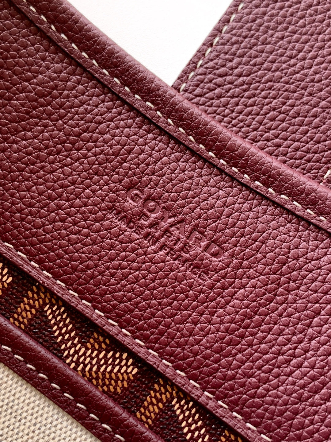 Maroon Goyard bag exterior with embossed logo and stitched edge seam detail