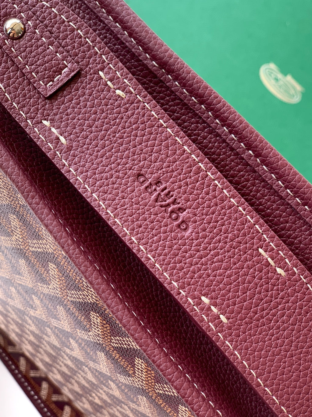 Maroon Goyard bag strap with contrast stitching and debossed logo on leather