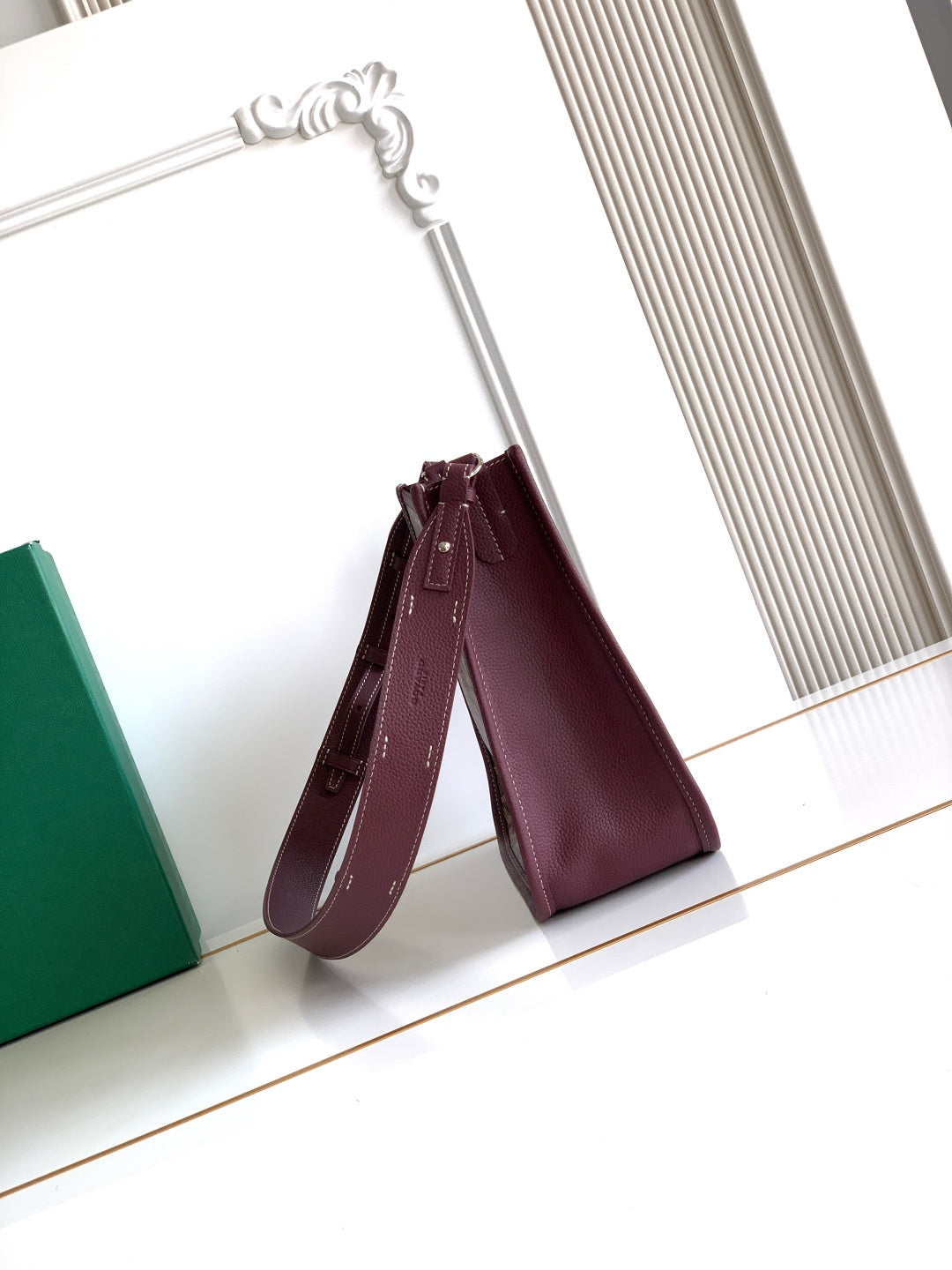 Maroon Goyard crossbody bag with short top handles and stitched logo detail