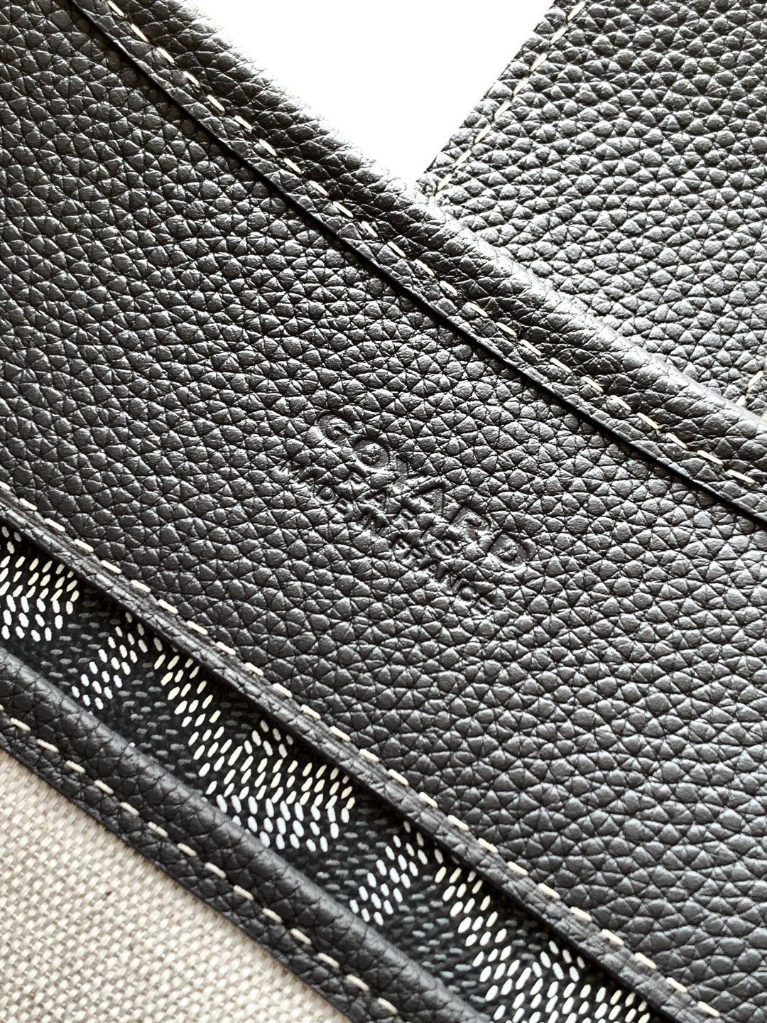 Goyard monogram bag close-up of pebbled leather exterior and seam lines, dark gray