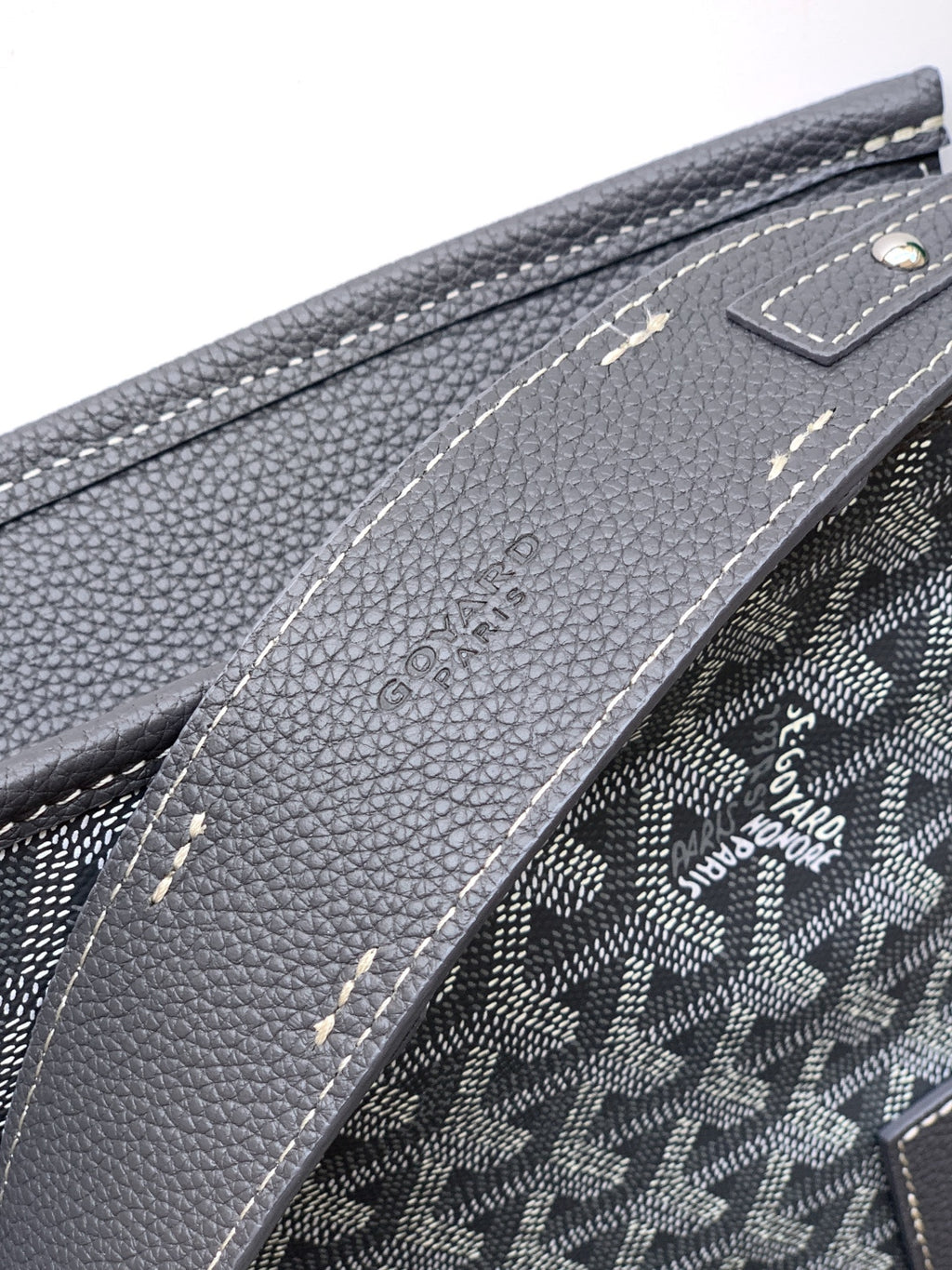 Goyard monogram bag close-up of textured leather trim and stitched side, dark gray