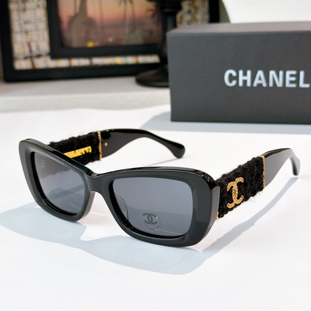 Dark gray sunglasses with black fabric temples and gold logo detail