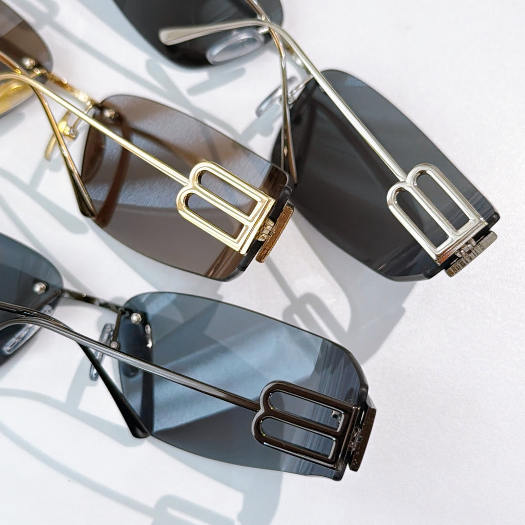 Close-up of shield sunglasses with gold frames and dark tinted lenses, logo on temples
