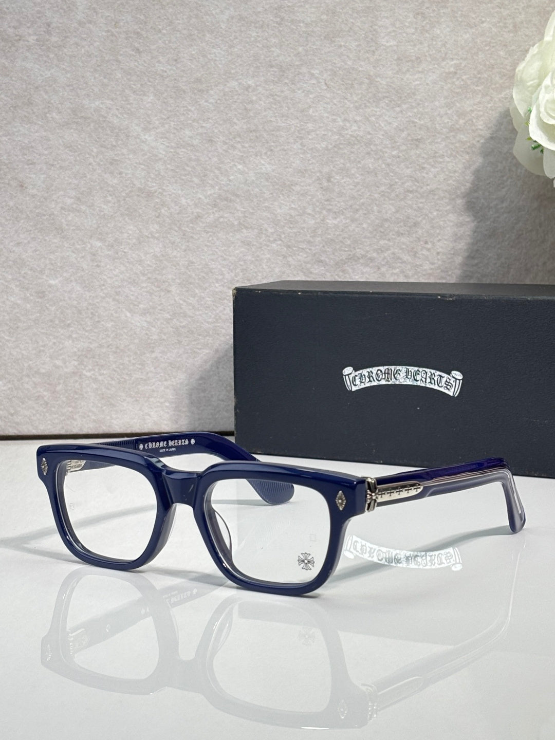 Chrome glasses with dark blue acetate frames, clear lenses, gold accents on temples