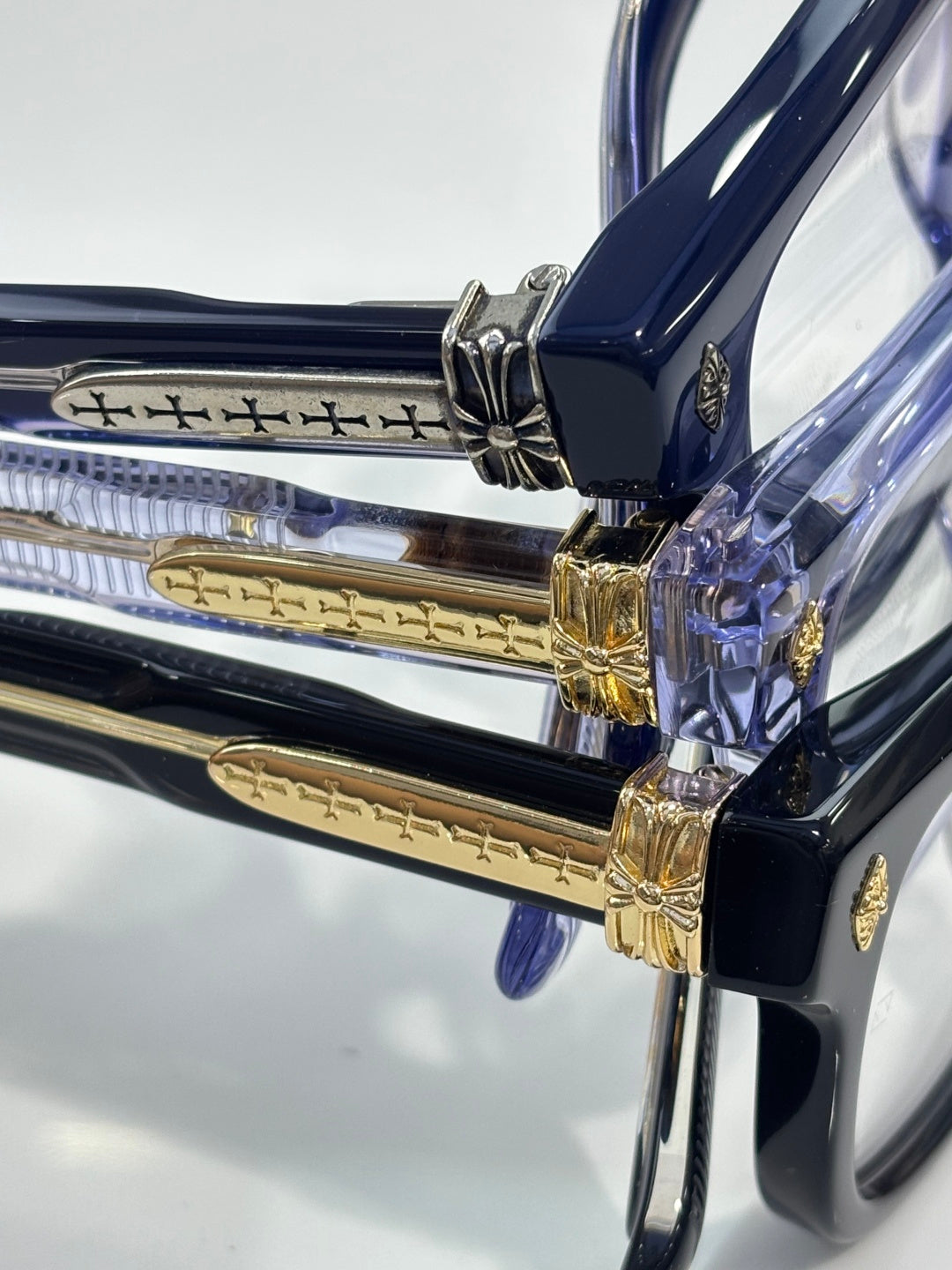 Chrome glasses close-up of blue frame hinge with gold decorative detailing