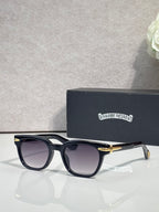 Glasses with black frames, dark lenses, and gold-tone temple accents.