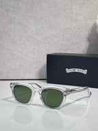 Glasses with clear frames and green-tinted lenses, with engraved temple detailing.