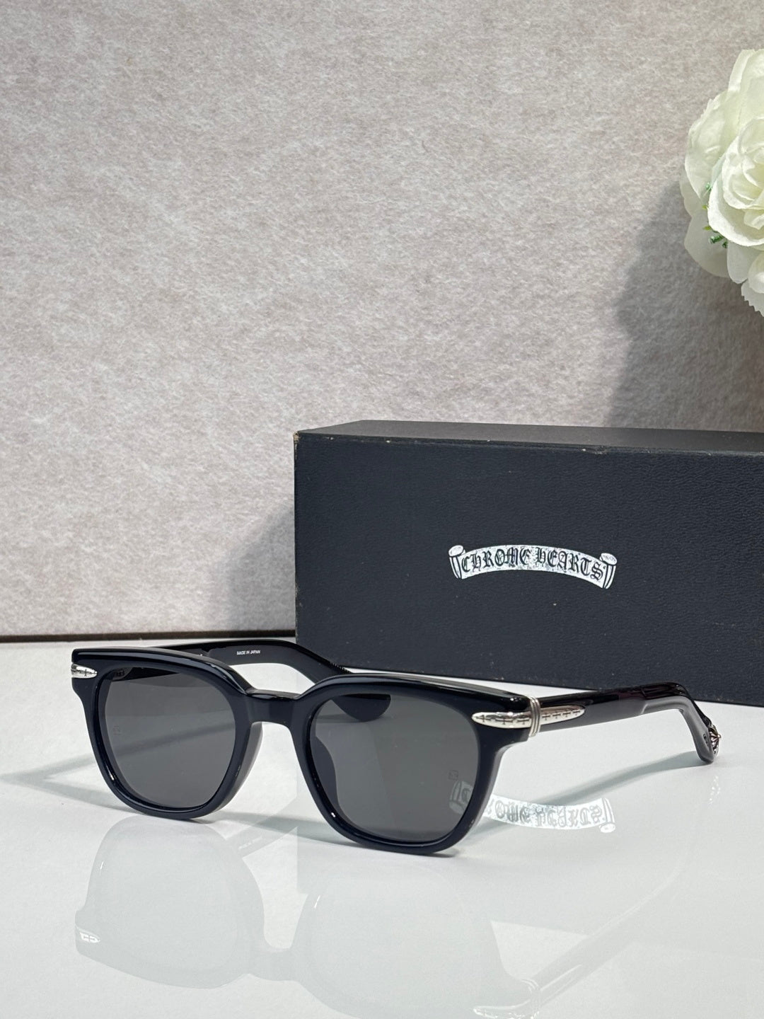 Glasses with black frames and dark lenses, shown with gold-tone side details.