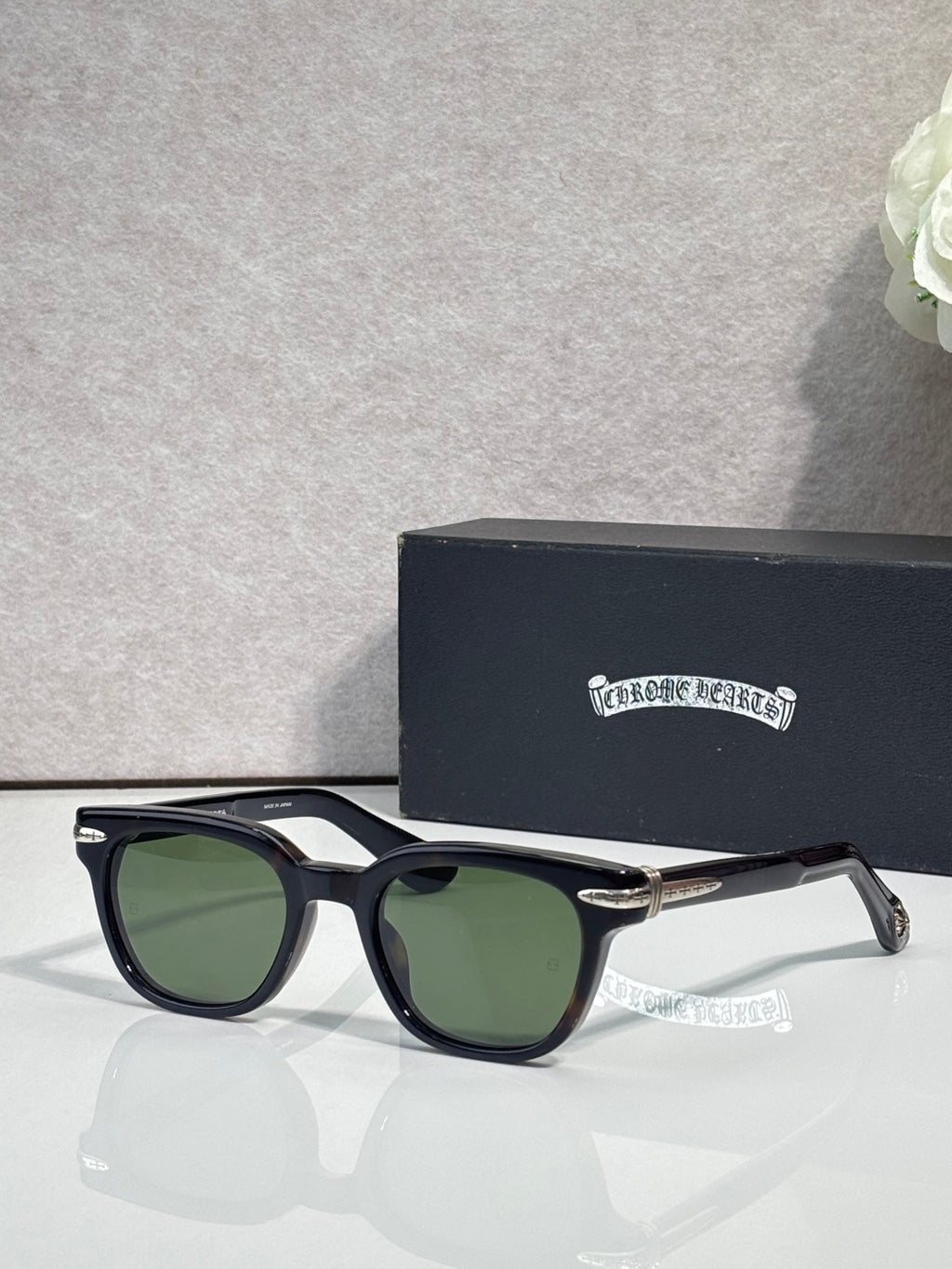 Glasses with black frames and green-tinted lenses, featuring gold-tone temple accents.
