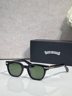 Glasses with black frames and green-tinted lenses, featuring gold-tone temple accents.