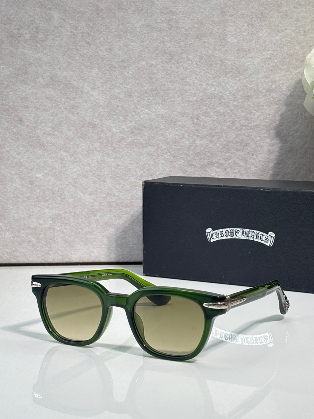 Glasses with dark green frames and green-tinted lenses, with gold-tone accents.