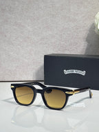 Glasses with black frames and amber-tinted lenses, with gold-tone temple accents.