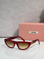 Red cat-eye sunglasses with dark lenses and gold logo detail at temples.