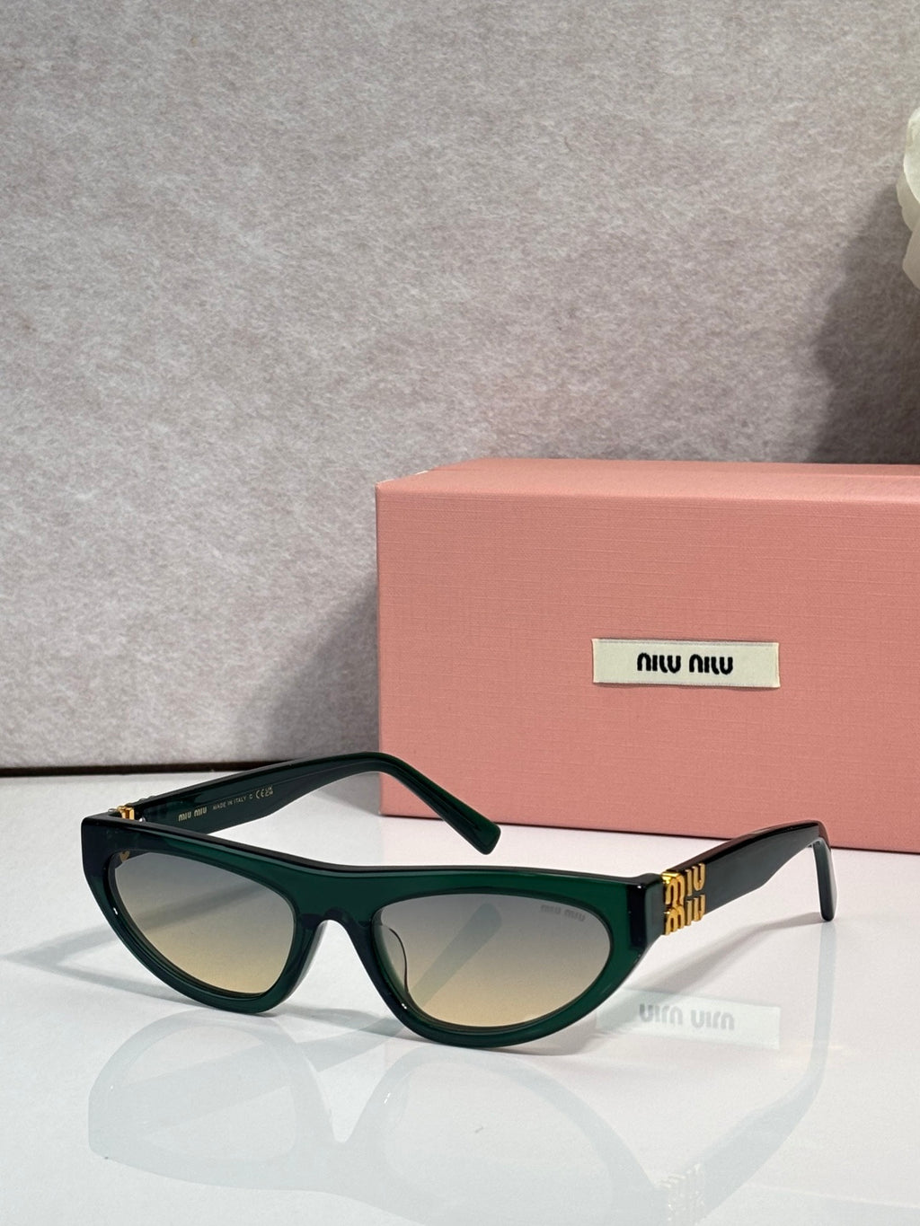 Dark green cat-eye sunglasses with dark lenses and gold logo detail at temples.