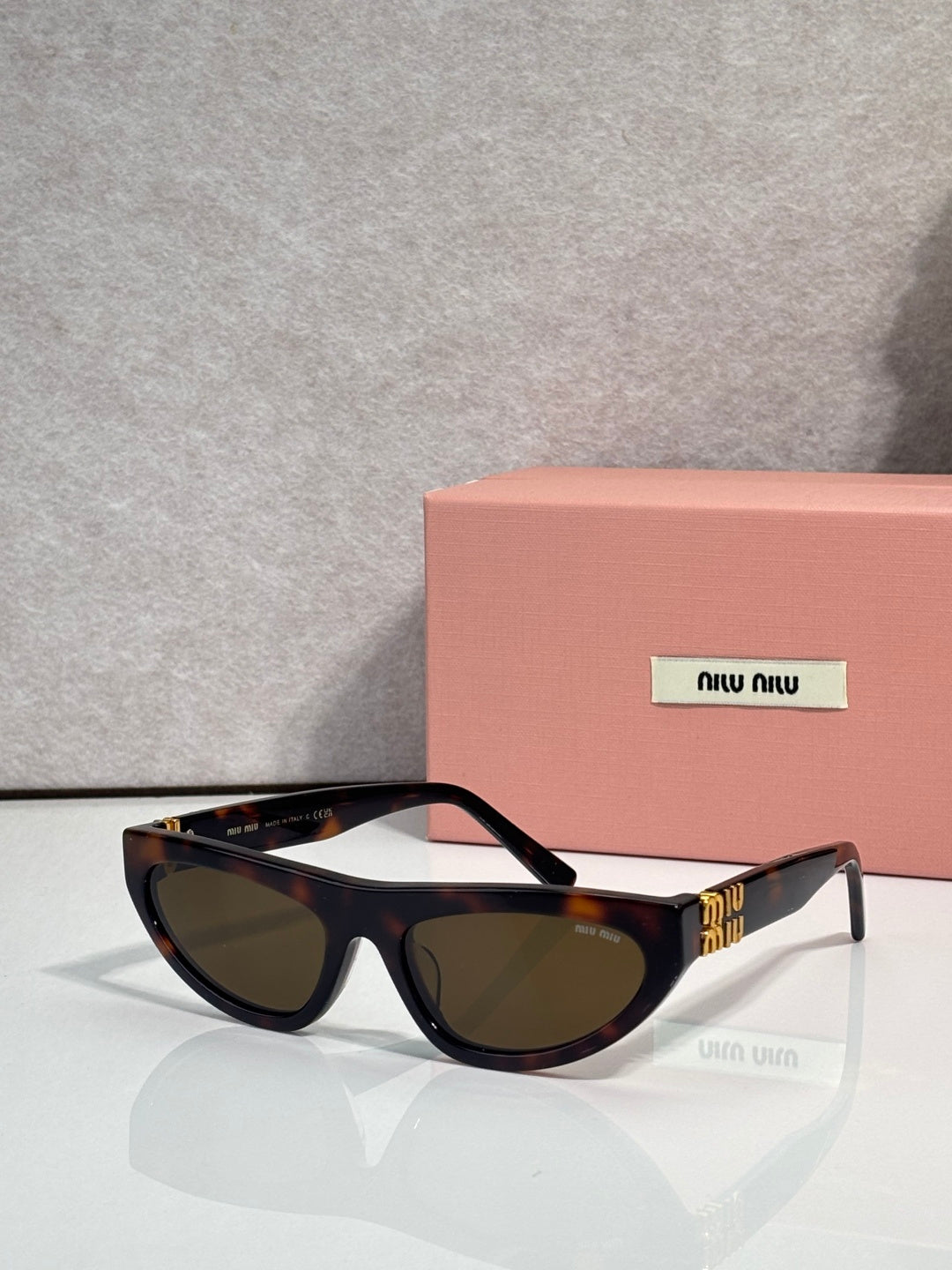 Black cat-eye sunglasses with dark lenses and gold logo detail at temples.