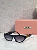 Black cat-eye sunglasses with dark lenses and gold logo detail at temples.
