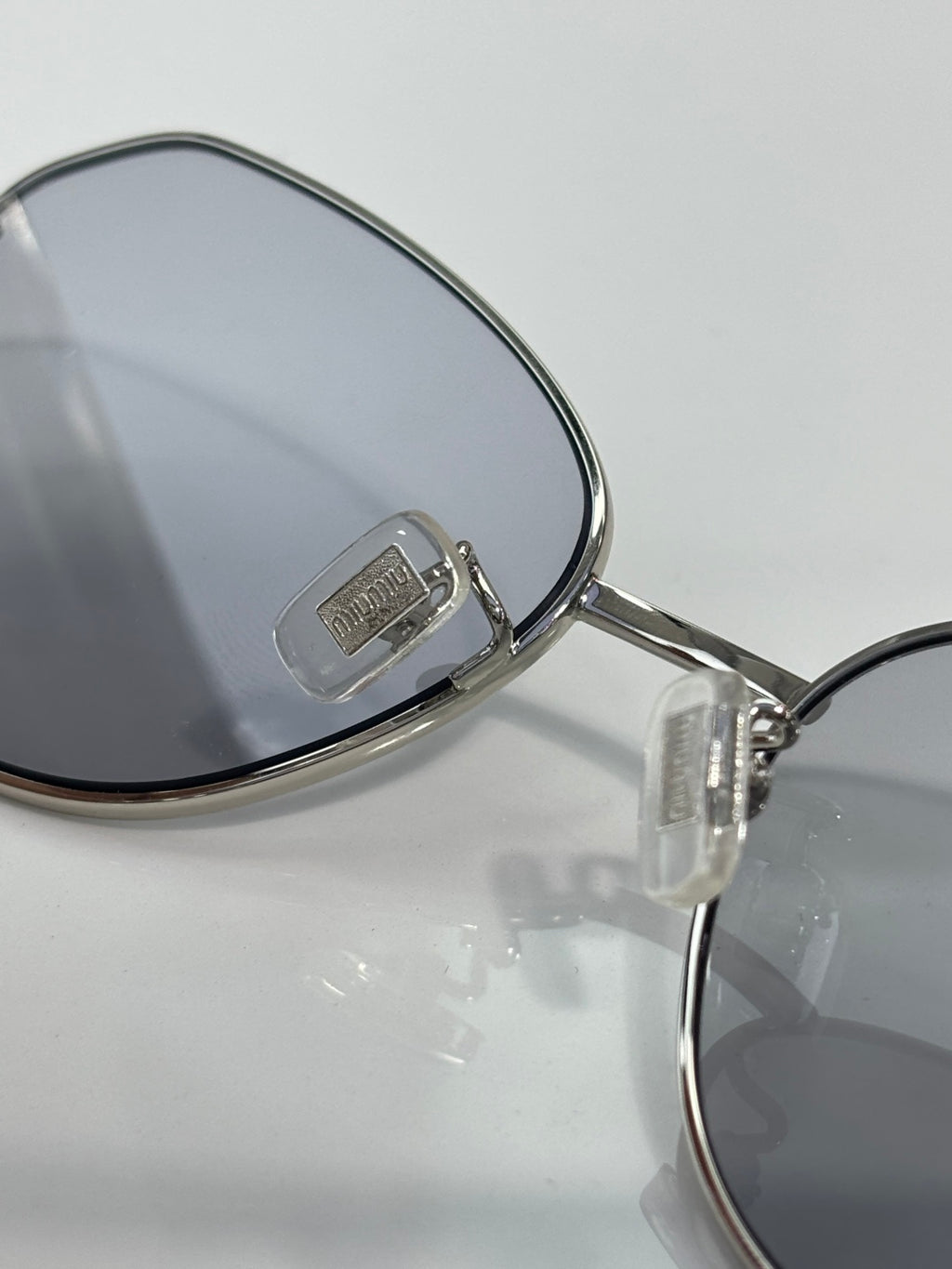 Metal sunglasses arm with Miu Miu logo and dark lens