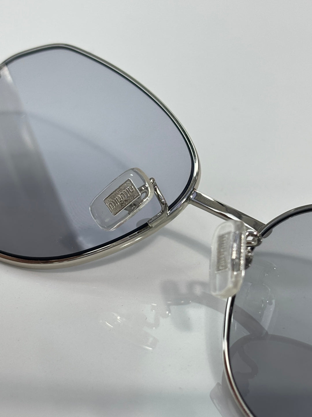 Metal sunglasses arm with Miu Miu logo and dark lens