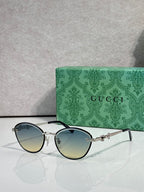 Gold metal sunglasses with blue gradient lenses and chain-link temple details