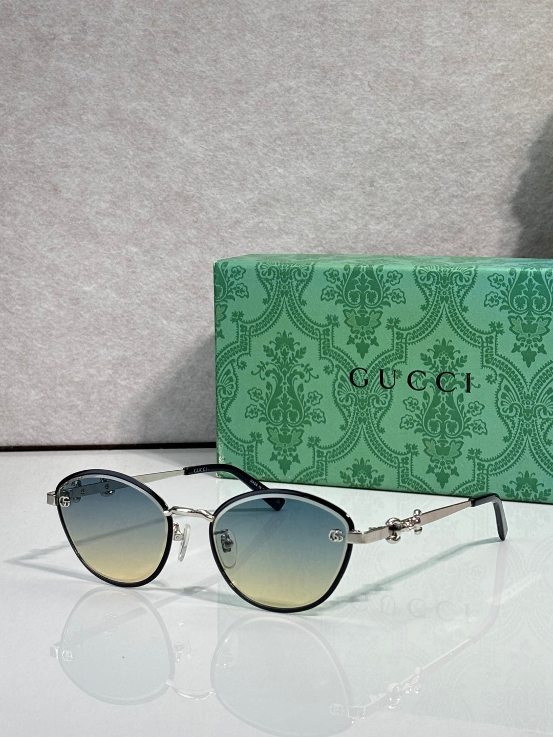 Gold metal sunglasses with blue gradient lenses and chain-link temple details