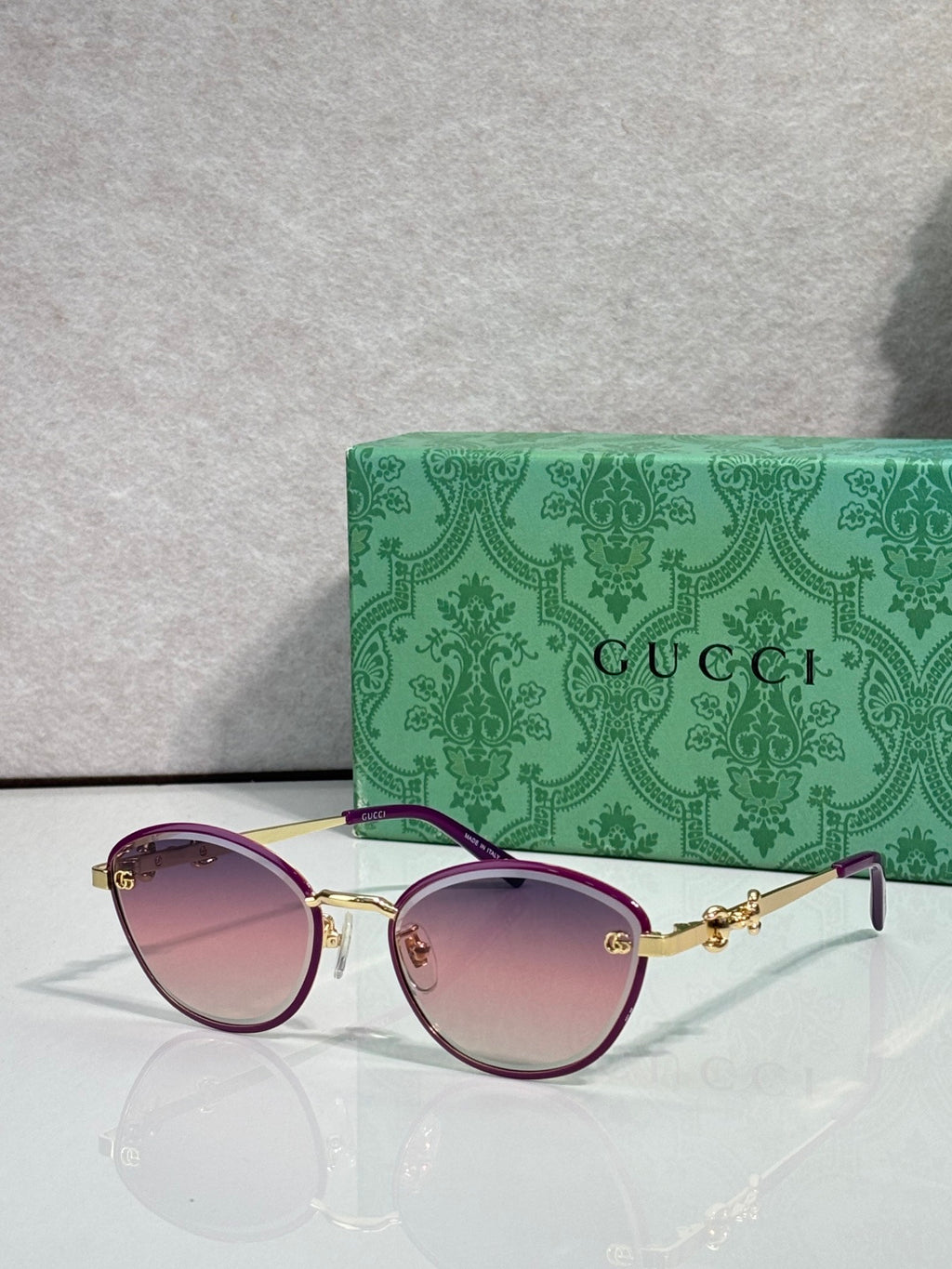 Gold metal sunglasses with pink gradient lenses and chain-link temple details