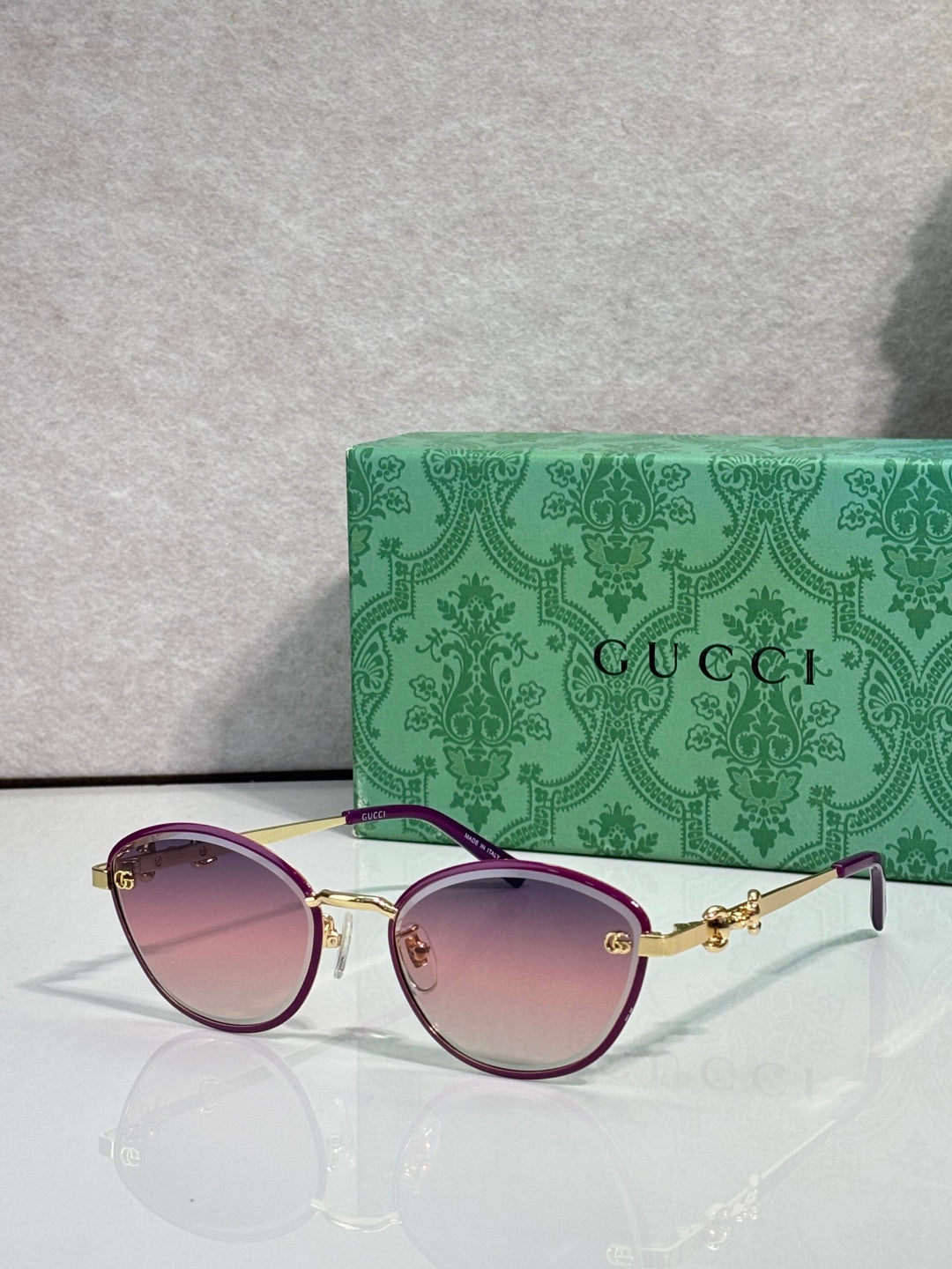 Gold metal sunglasses with pink gradient lenses and chain-link temple details