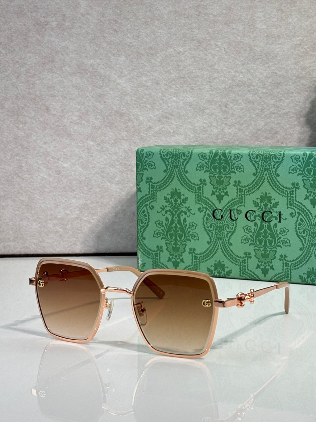 Gucci sunglasses with tan frames and amber gradient lenses, square corners.