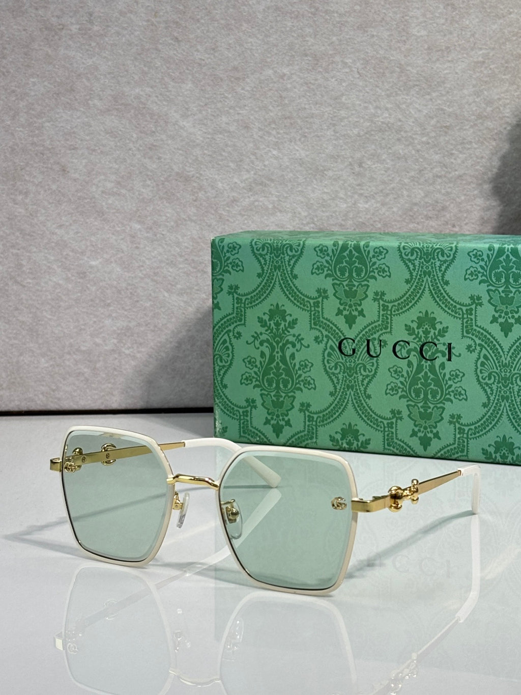 Gucci sunglasses with white frames and light green gradient lenses, square corners.